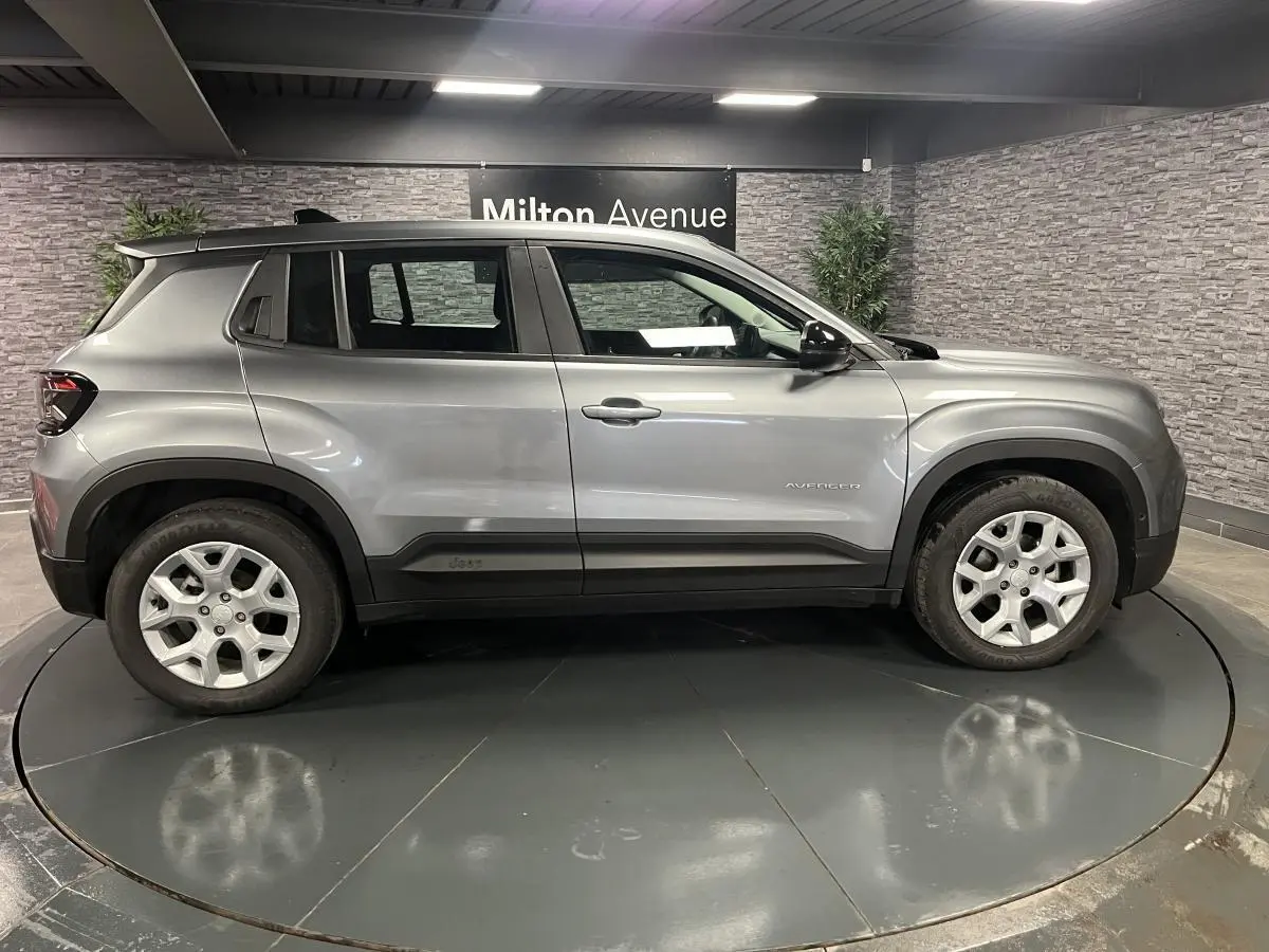 Vue de profil côté gauche d'un Jeep Avenger gris métallisé avec jantes alliage 17 pouces en showroom.