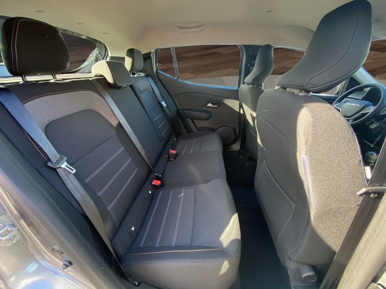 Vue intérieure côté gauche montrant les sièges arrière noirs et le tableau de bord partiel d'une Dacia Sandero Stepway 2025.