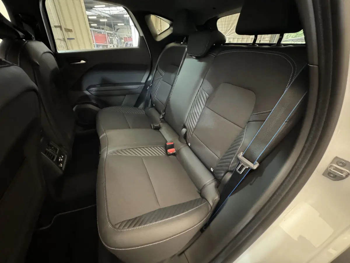 Vue intérieure côté droit montrant la banquette arrière noire avec surpiqûres bleues du Renault Captur blanc esprit Alpine E-Tech 2025.