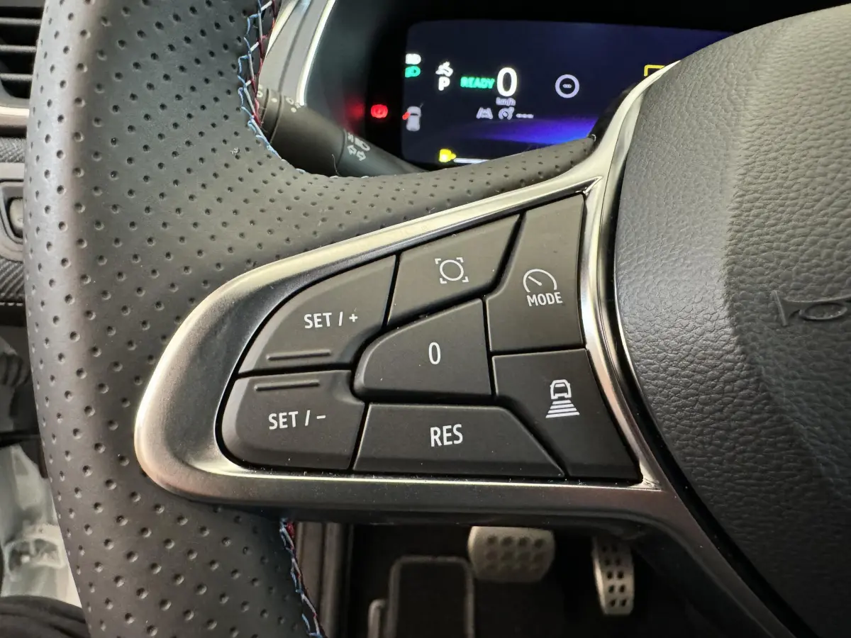 Gros plan sur les commandes du volant cuir perforé du Renault Captur blanc esprit Alpine E-Tech 2025, avec affichage numérique.