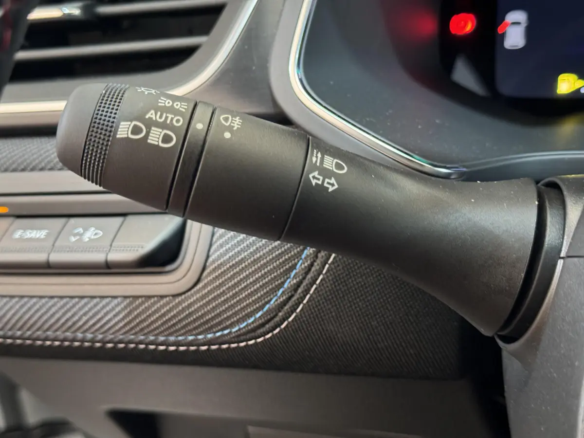 Gros plan sur la commande des feux et clignotants dans l'habitacle du Renault Captur blanc esprit Alpine E-Tech 2025.
