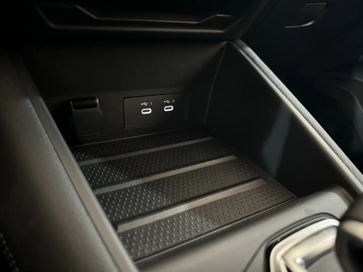 Gros plan sur la zone de recharge et ports USB doubles dans le coffre central du Renault Captur blanc esprit Alpine E-Tech 2025.