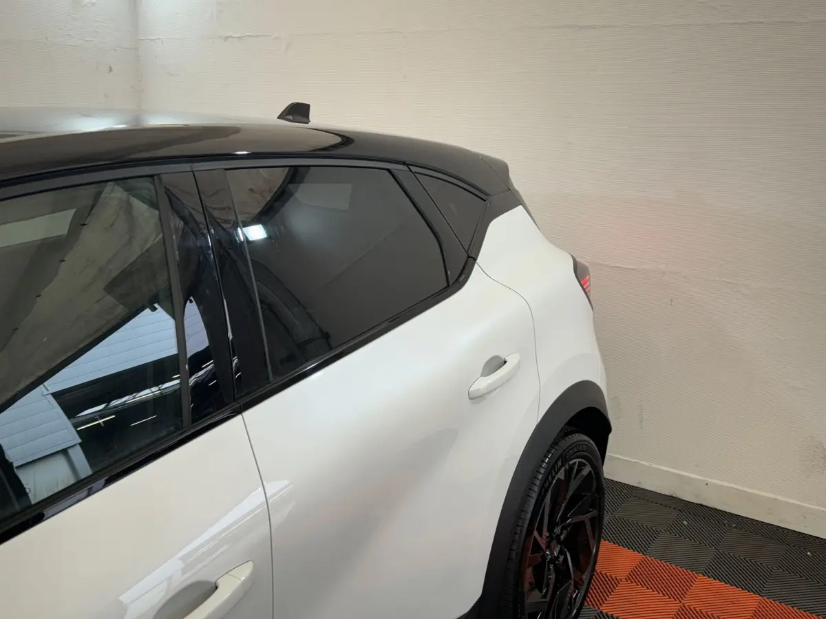 Vue arrière côté gauche du Renault Captur blanc esprit Alpine E-Tech avec toit noir et jantes noires sportives.