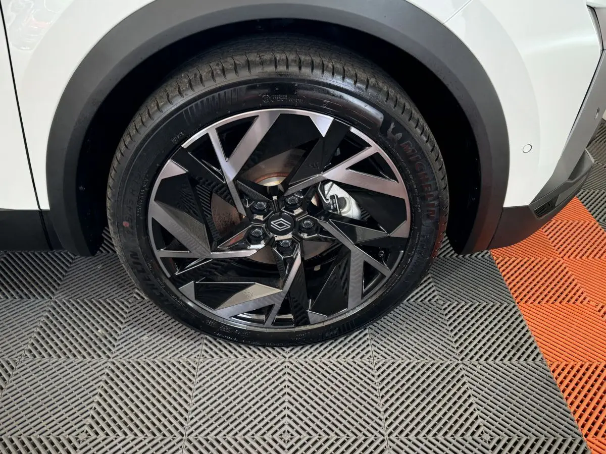 Gros plan sur la roue avant droite blanche du Renault Captur Esprit Alpine E-Tech avec jante noire et argentée au design géométrique.