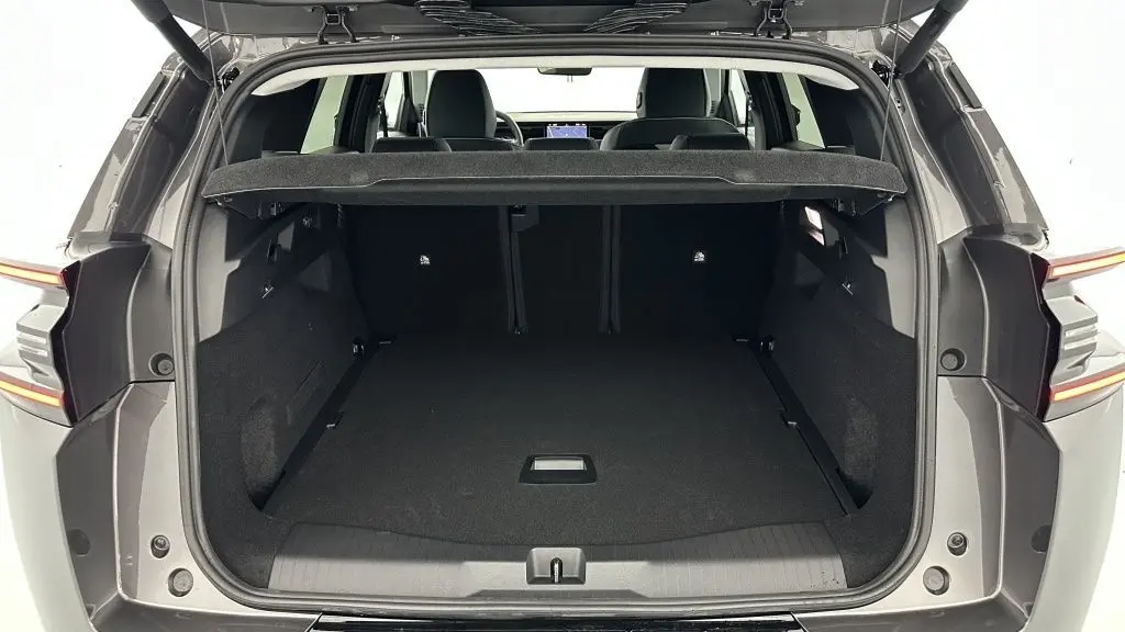 Coffre ouvert vu de l'arrière d'un Citroën C5 Aircross hybride gris platinium, montrant un espace de chargement vide et spacieux.