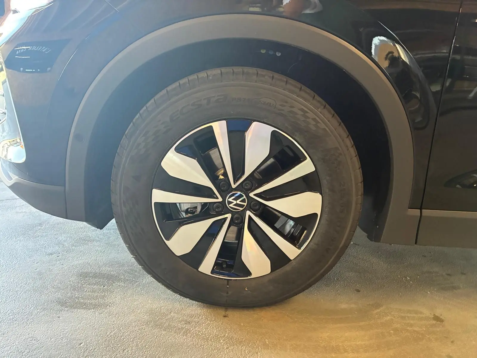 Gros plan sur la roue avant gauche du Volkswagen Tiguan noir Grenadilla Métal avec jante alliage bicolore distinctive.