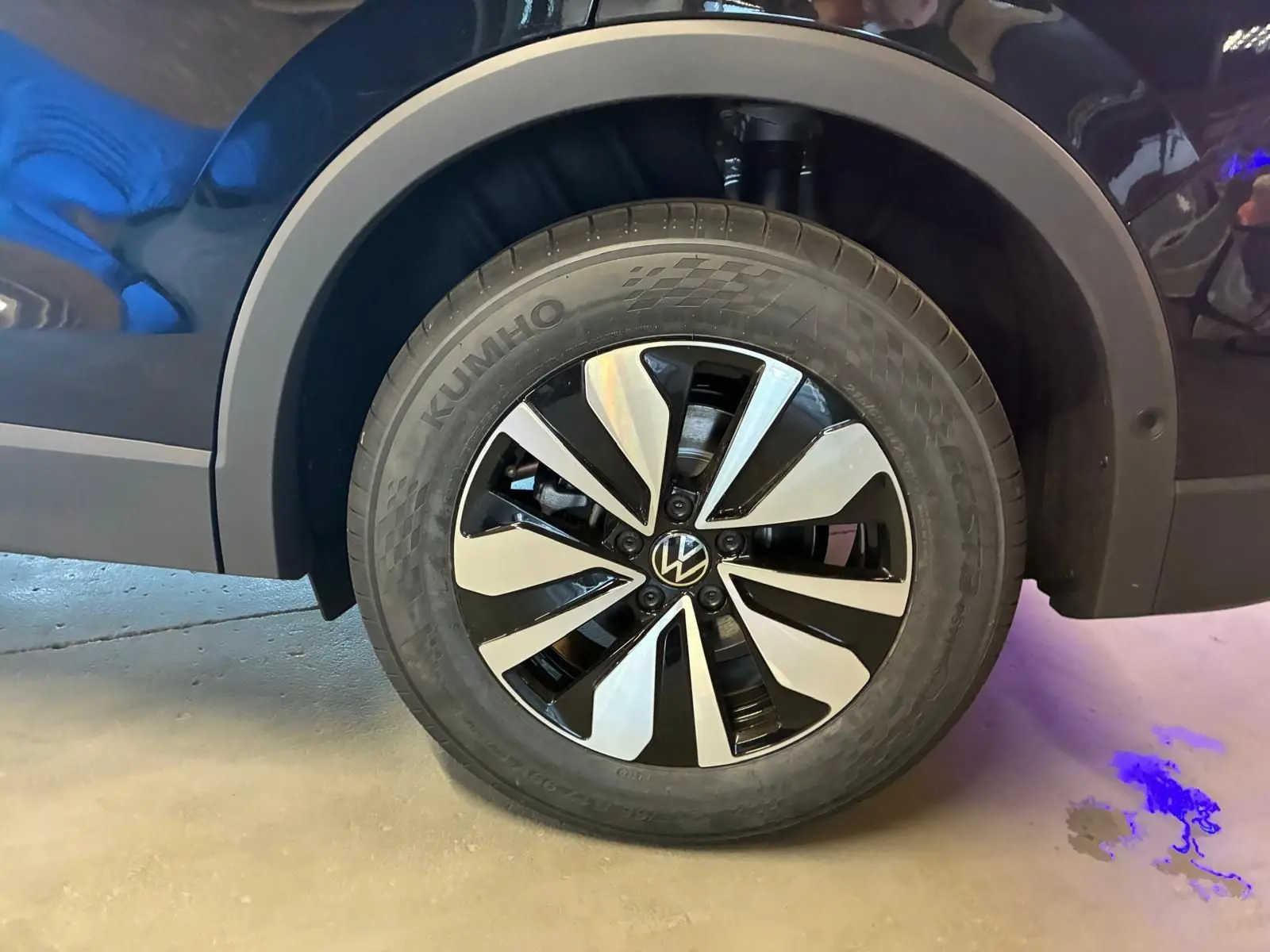Gros plan sur la roue avant gauche noire grenadilla métal du Volkswagen Tiguan 1.5 TSI 130 DSG LIFE 30 YEARS avec jante bicolore.