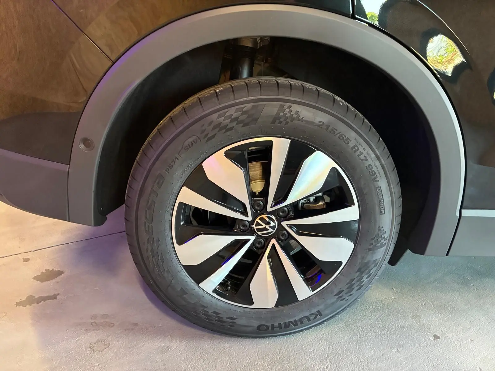 Gros plan sur la roue avant droite du Volkswagen Tiguan noir Grenadilla, mettant en valeur la jante bi-ton moderne.