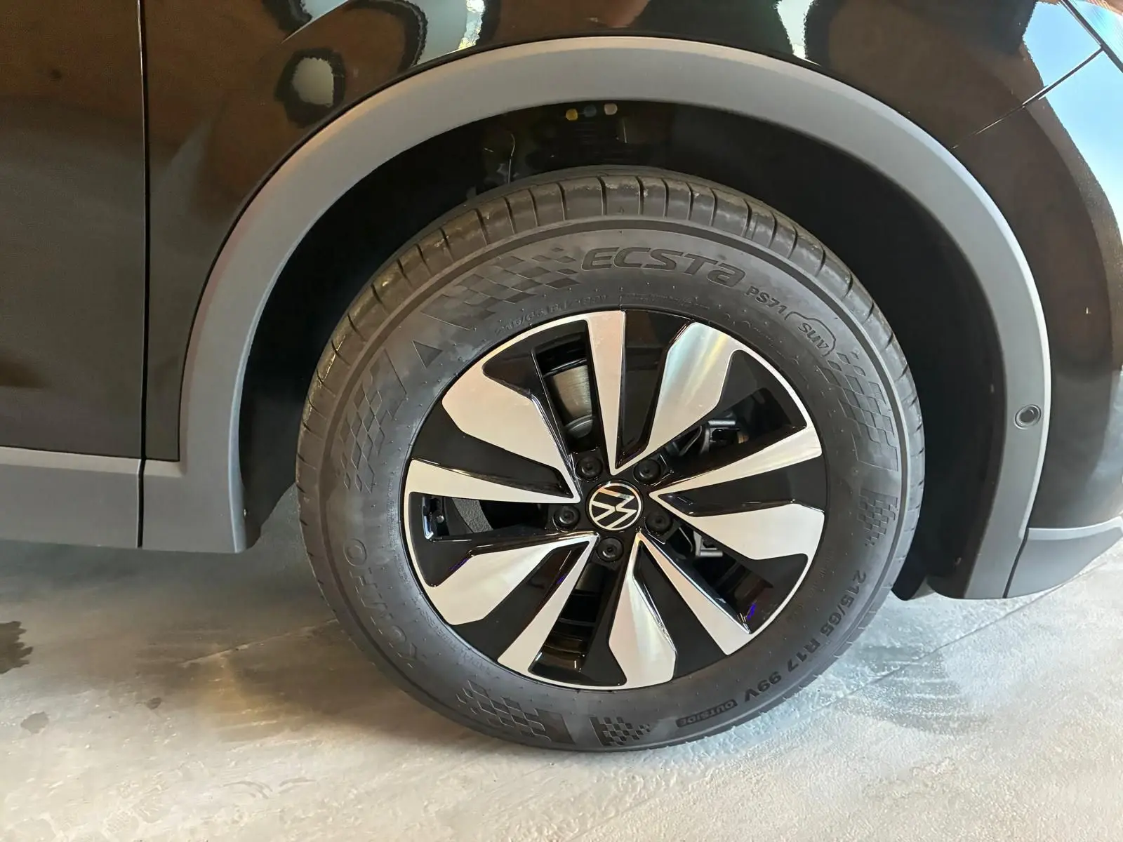 Gros plan sur la roue avant droite noire grenadilla métal du Volkswagen Tiguan 1.5 TSI 130 DSG Life 30 Years avec jante alliage bicolore.