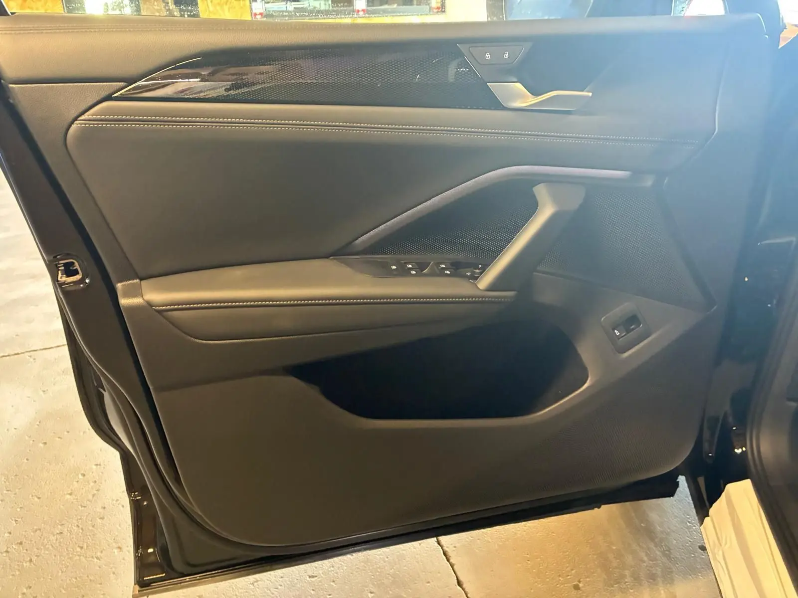 Vue intérieure côté gauche de la porte avant noire du Volkswagen Tiguan 2026 avec commandes de vitres et poignée intégrée.