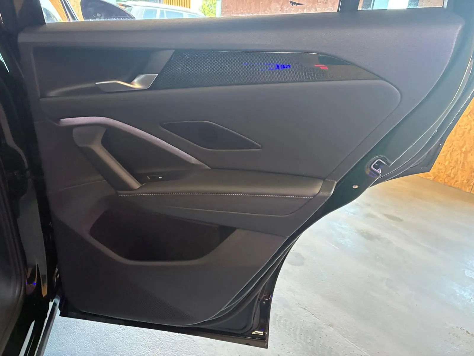 Vue intérieure côté gauche de la porte arrière noire grenadilla métal du Volkswagen Tiguan 2026 avec garniture en tissu et cuir.