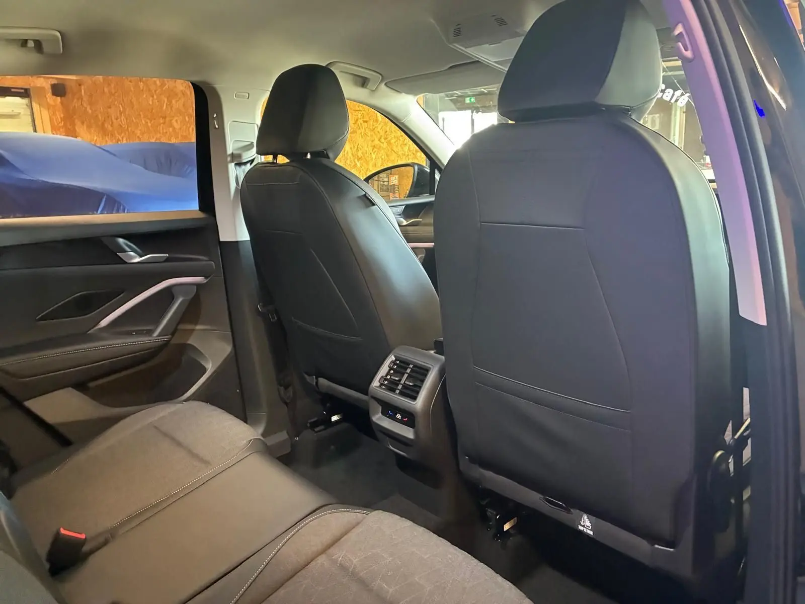 Vue intérieure arrière du Volkswagen Tiguan 2026 noir Grenadilla, sièges en tissu et cuir, avec commandes de climatisation arrière.