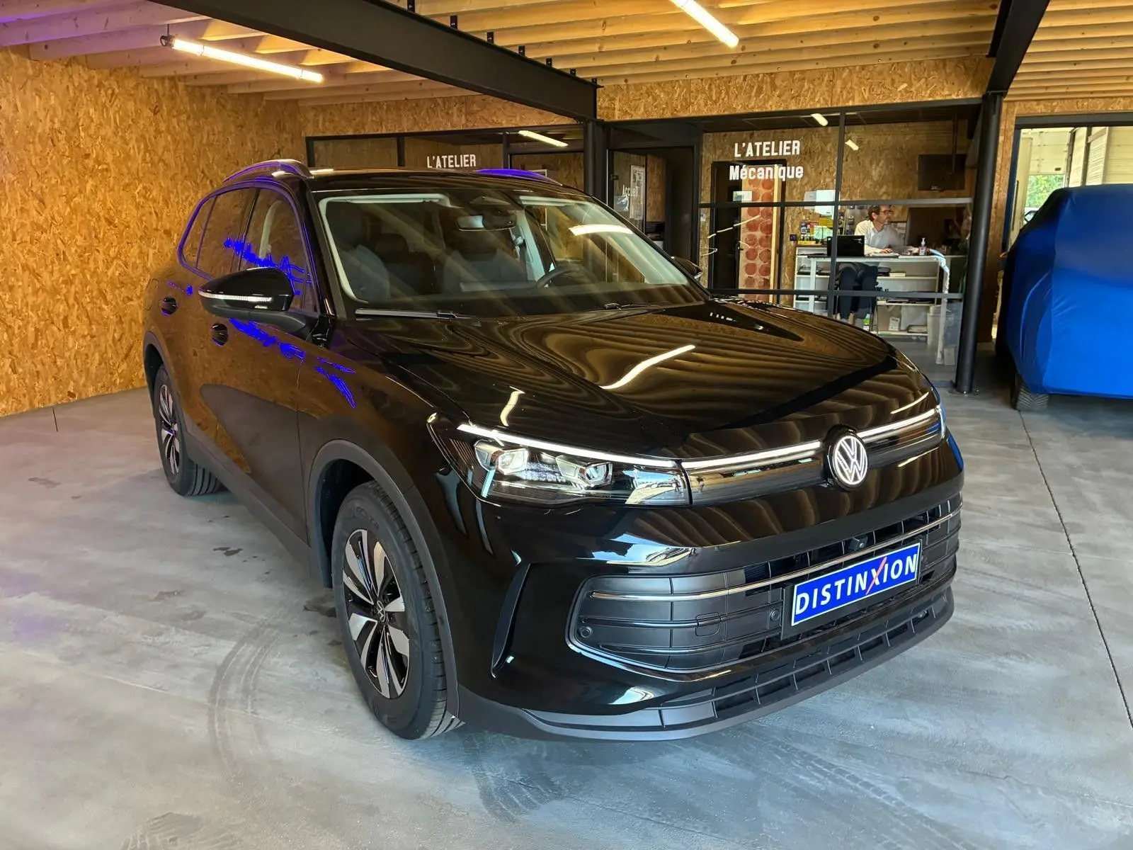 Volkswagen Tiguan 1.5 TSI noir grenadilla métal, vue 3/4 avant droit en intérieur d'atelier.