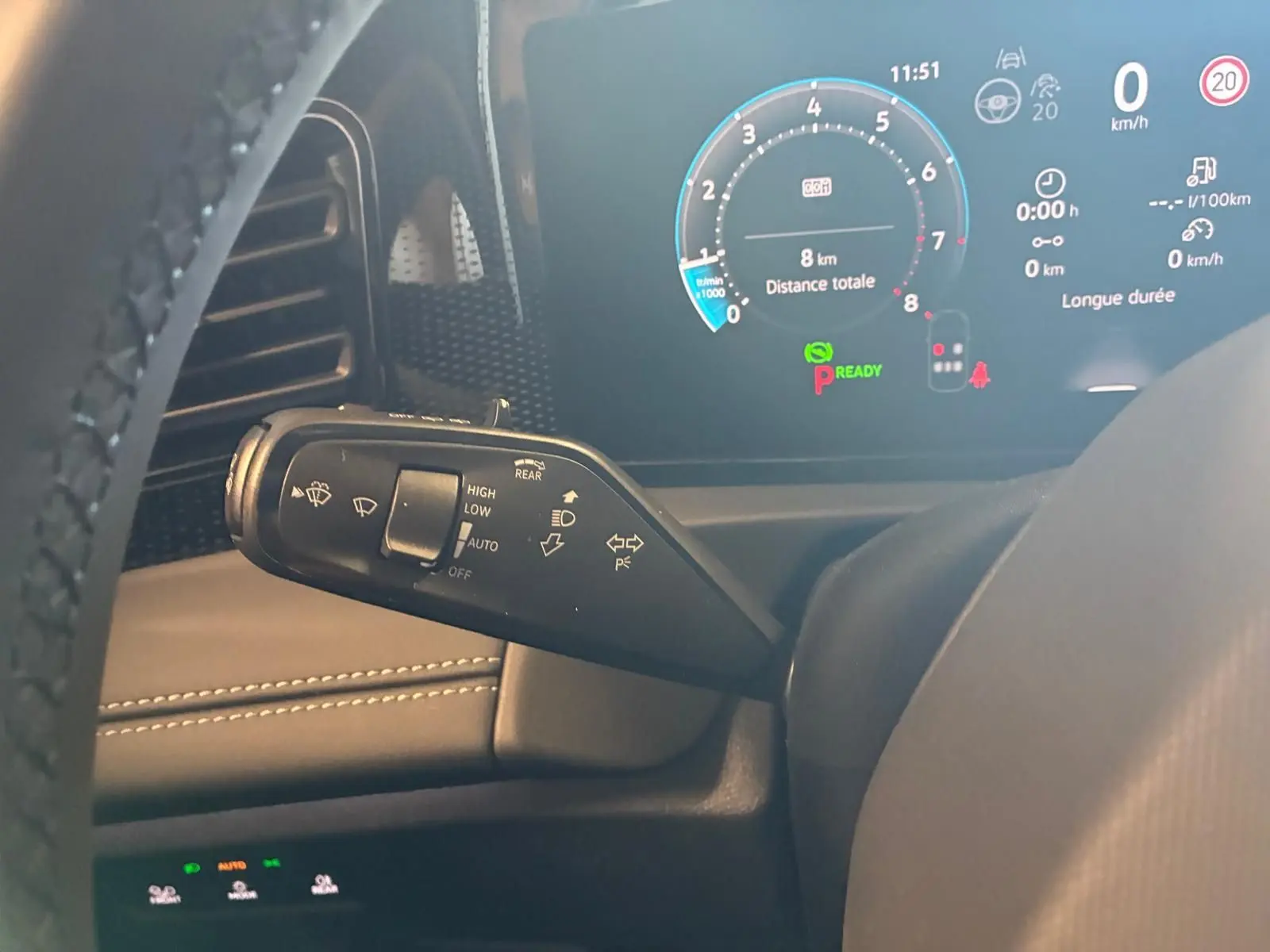 Gros plan sur la manette de commandes au volant du Volkswagen Tiguan noir Grenadilla, avec tableau de bord numérique en arrière-plan.