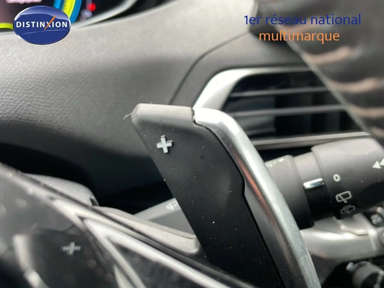 Gros plan sur la palette de changement de vitesse + au volant d’un Peugeot 3008 gris Artense 2024 hybride rechargeable.