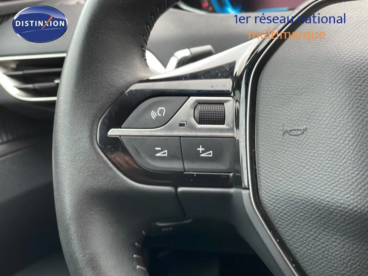 Gros plan sur les commandes gauche du volant cuir noir du Peugeot 3008 1.6 Hybrid 2024, intérieur moderne et épuré.