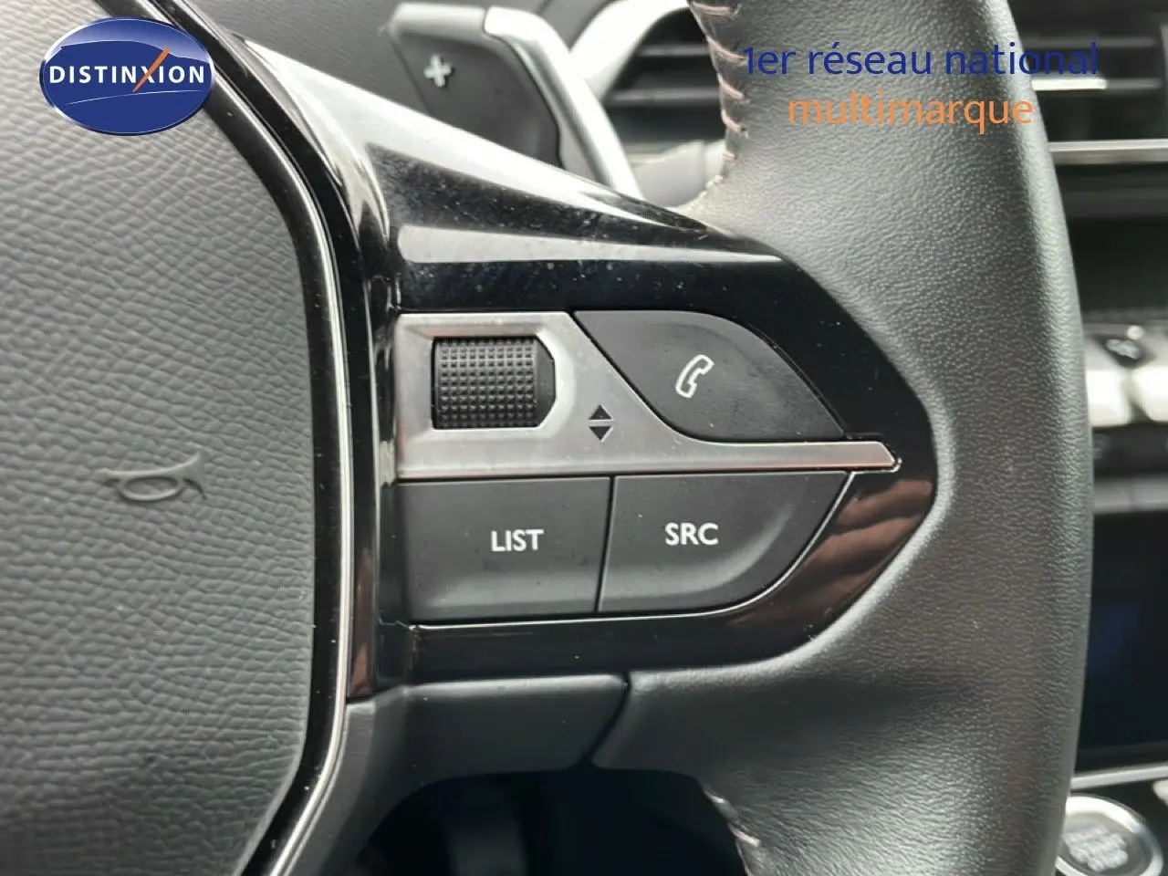 Gros plan sur les commandes gauche du volant cuir noir du Peugeot 3008 gris Artense 2024, boutons LIST et SRC visibles.