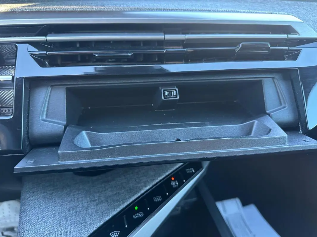 Gros plan intérieur sur la boîte à gants ouverte du Peugeot 3008 blanc, version Hybrid 145 e-DCS6 Allure.