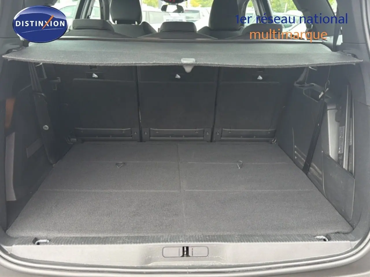 Coffre ouvert vu de l'arrière d'un Peugeot 5008 bleu Célèbes Métal, avec banquette arrière rabattue et cache-bagages déployé.