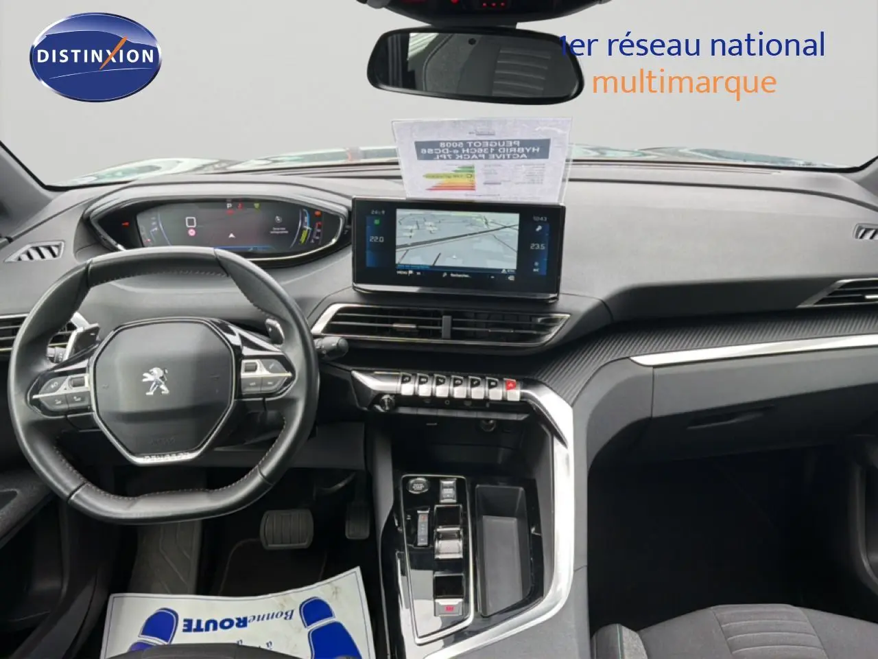 Vue intérieure du tableau de bord du Peugeot 5008 Hybrid 2024 avec écran central tactile et volant compact multifonctions.