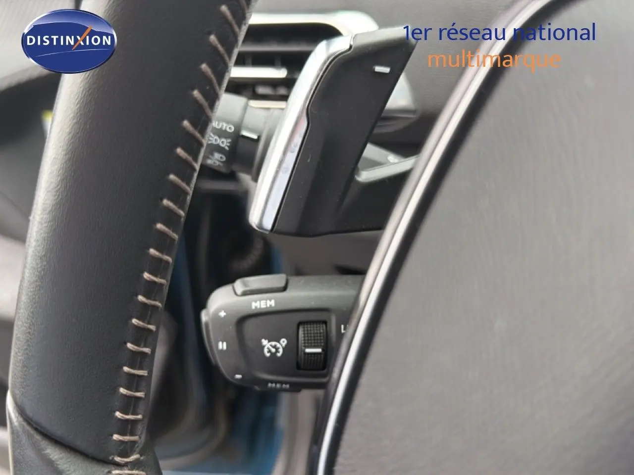 Gros plan sur la commande de régulateur de vitesse derrière le volant en cuir noir du Peugeot 5008 bleu Celebes.