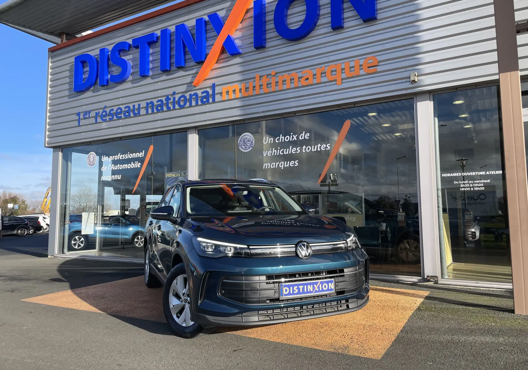 Volkswagen Tiguan 2.0 TDI 150 DSG Life Plus en Nightshade Blue, vue 3/4 avant devant un showroom Distinxion.