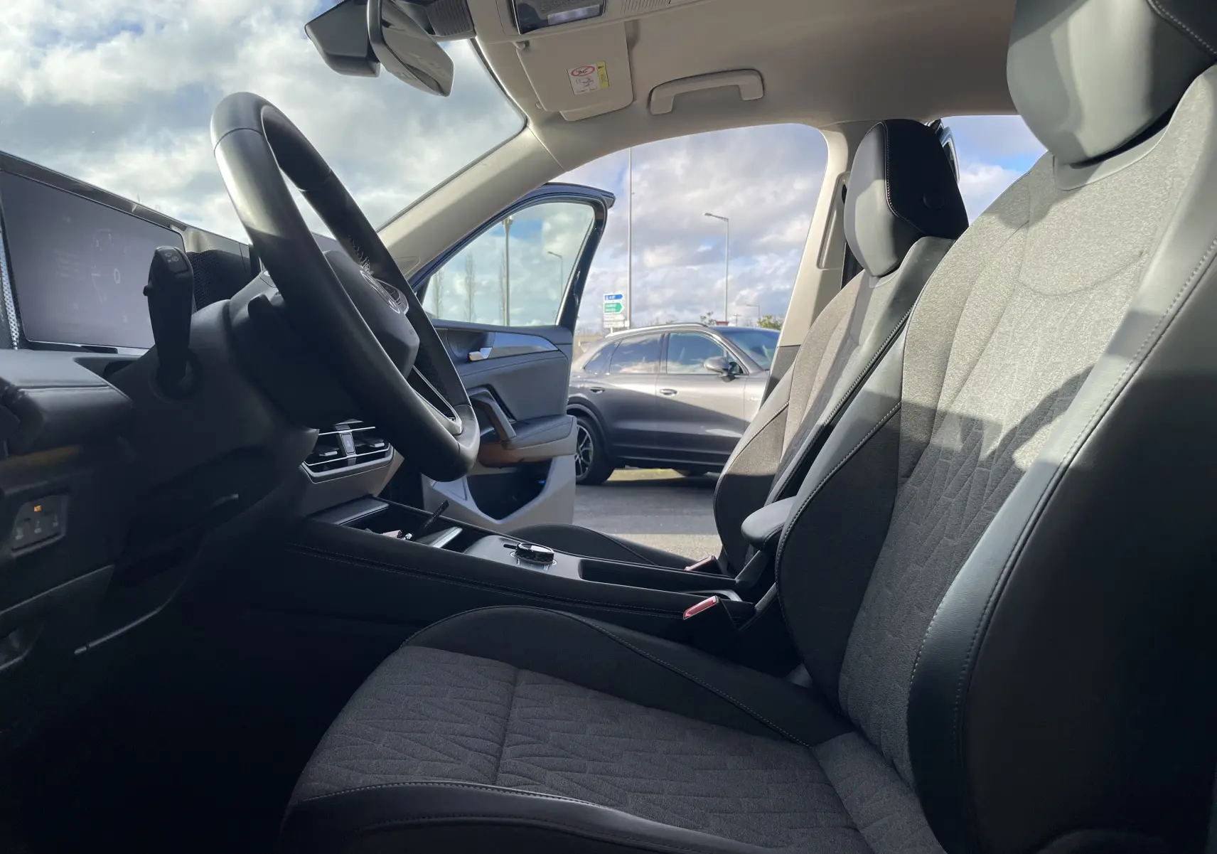 Vue intérieure côté conducteur du Volkswagen Tiguan 2024 bleu Nightshade, sièges gris-noir et volant cuir visible.