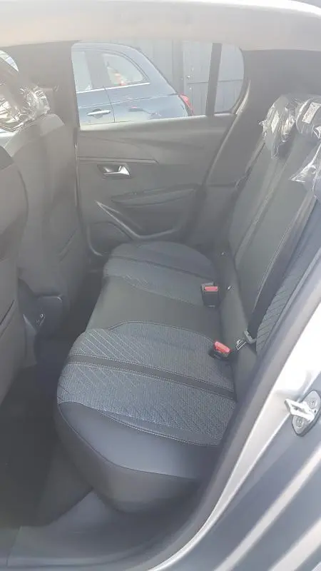 Vue intérieure de la banquette arrière droite de la Peugeot 208 Hybrid 110 gris, sièges en tissu et cuir avec ceintures rouges.