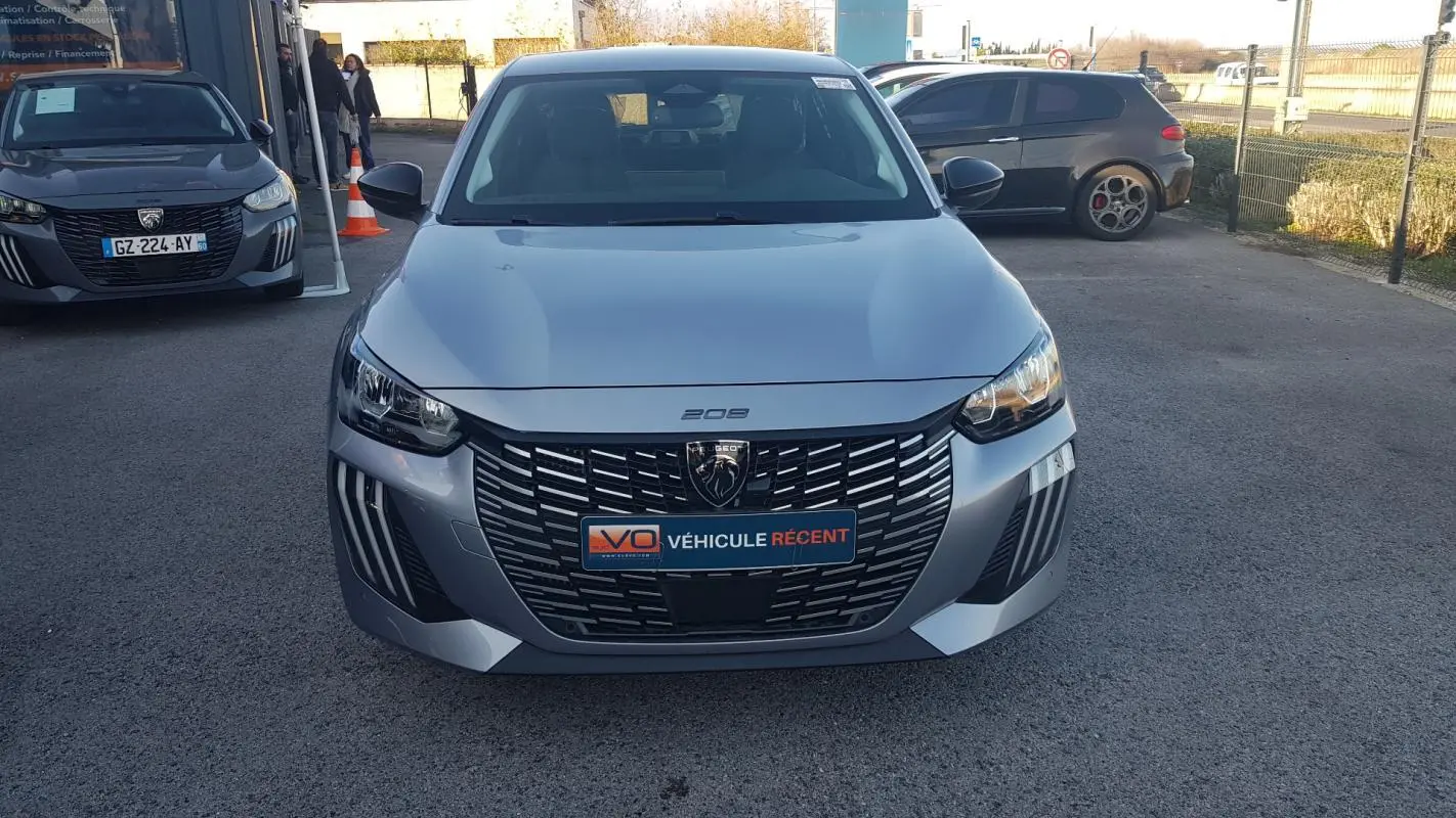 Vue avant frontale d’une Peugeot 208 gris métallisé avec calandre noire et feux diurnes LED distinctifs.