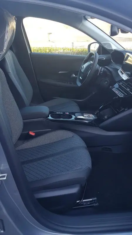 Vue intérieure côté conducteur de la Peugeot 208 Hybrid 110 gris, avec sièges tissu et tableau de bord moderne.