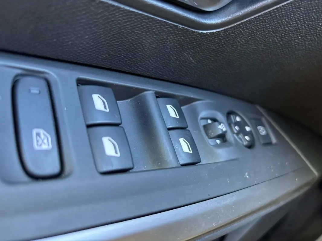 Gros plan sur les commandes des vitres électriques et rétroviseurs côté gauche d’un Peugeot 3008 gris Hybrid 145 e-DCS6 Allure.
