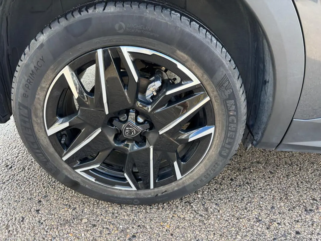 Gros plan sur la roue avant droite du Peugeot 3008 gris 2025 avec jante alliage noire et argentée de 19 pouces.