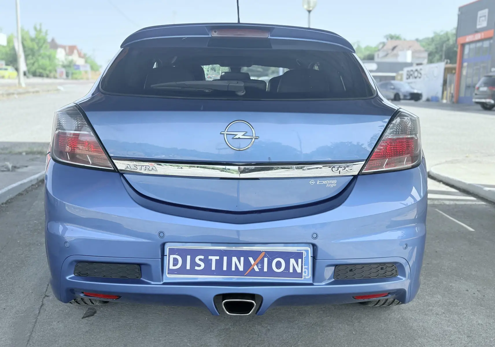 Vue arrière d'une Opel Astra OPC bleue de 2008 avec échappement central et feux arrière fumés.