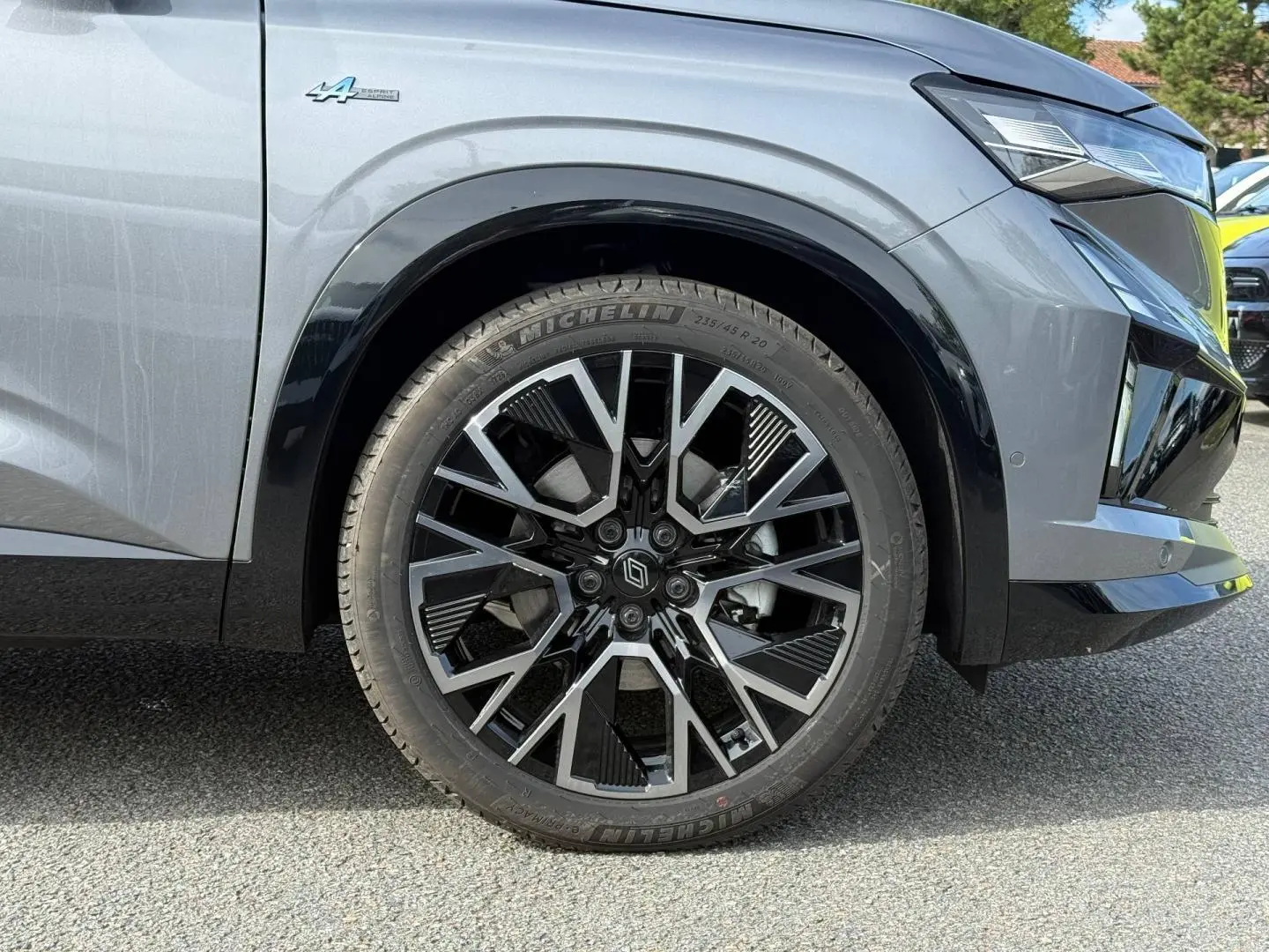 Gros plan sur la roue avant droite du Renault Austral gris Schiste satin avec jante alu noire et argentée et badge Alpine.