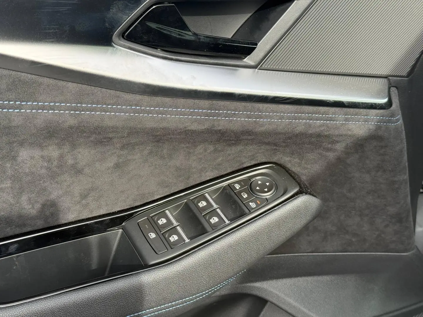 Détail de la porte côté conducteur du Renault Austral 2026, revêtement noir avec surpiqûres bleues et commandes de vitres.