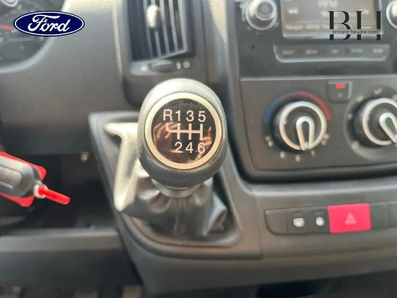 Gros plan sur le levier de vitesses manuel du Citroën Jumper blanc, avec tableau de bord et commandes de climatisation visibles.