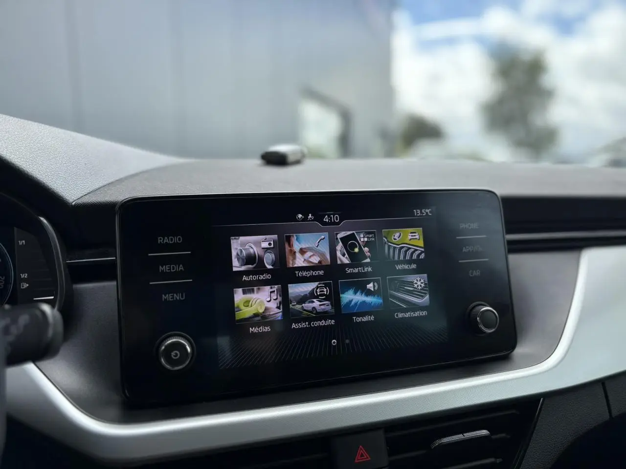 Écran tactile central du Skoda Kamiq Ambition 2024, affichant les menus SmartLink et assistances à la conduite.
