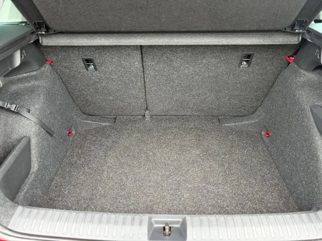 Coffre ouvert du Skoda Kamiq 2024, vue intérieure montrant le revêtement gris et les fixations ISOFIX rouges.