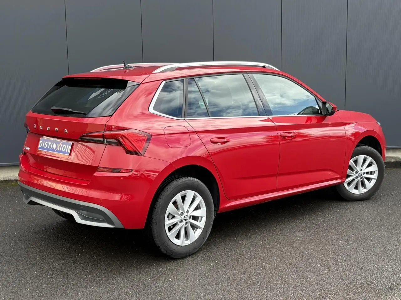 Vue 3/4 arrière droite d'un Skoda Kamiq 2024 rouge Velvet avec vitres arrière surteintées et jantes alliage 16 pouces.