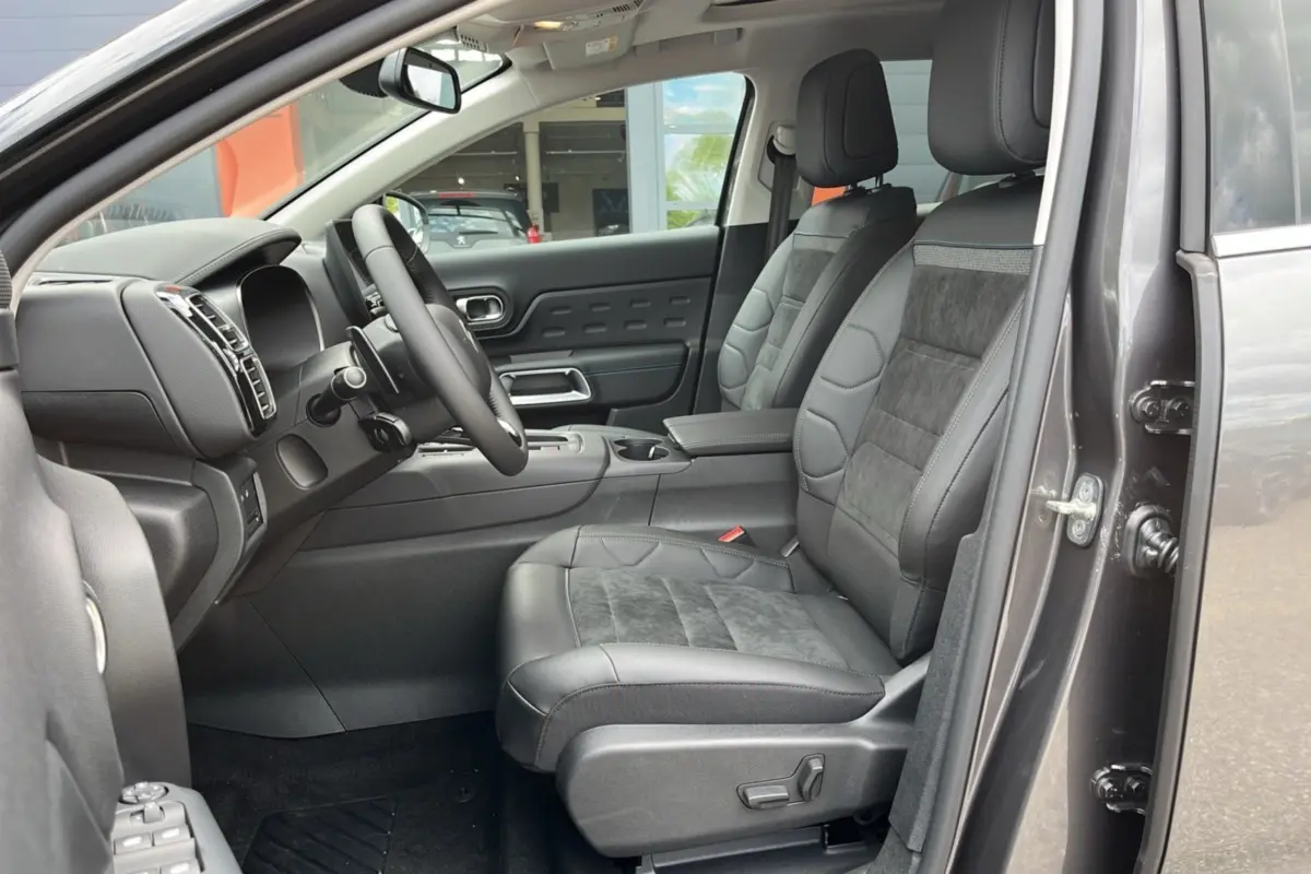 Intérieur avant droit du Citroën C5 Aircross Hybrid 2025 avec sièges cuir et alcantara gris, tableau de bord moderne et volant multifonction.