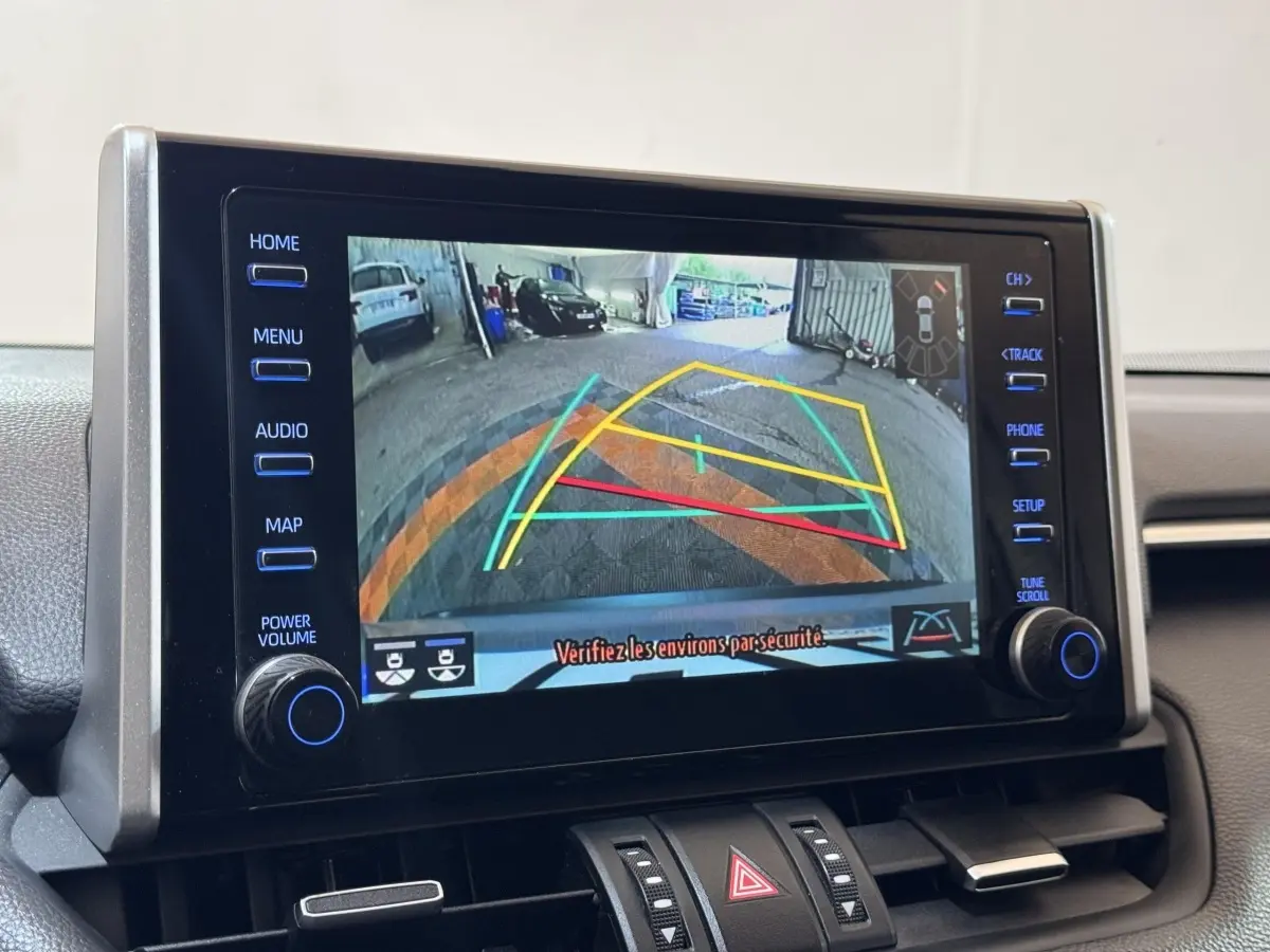 Écran tactile central montrant la caméra de recul avec guidage dynamique du Toyota RAV4 hybride gris clair, vue intérieure frontale.