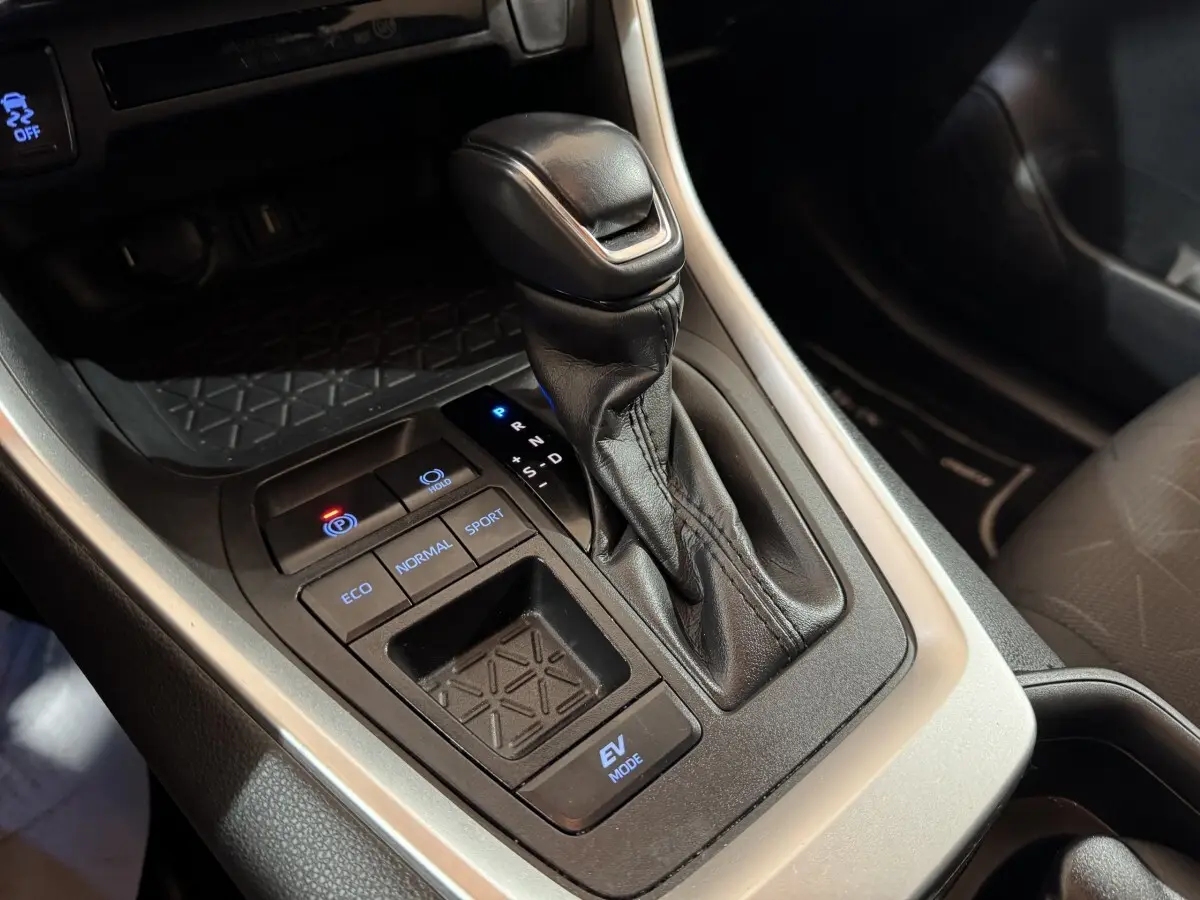 Gros plan sur la console centrale noire avec levier de vitesse automatique et boutons modes conduite du Toyota RAV4 gris clair 2021.