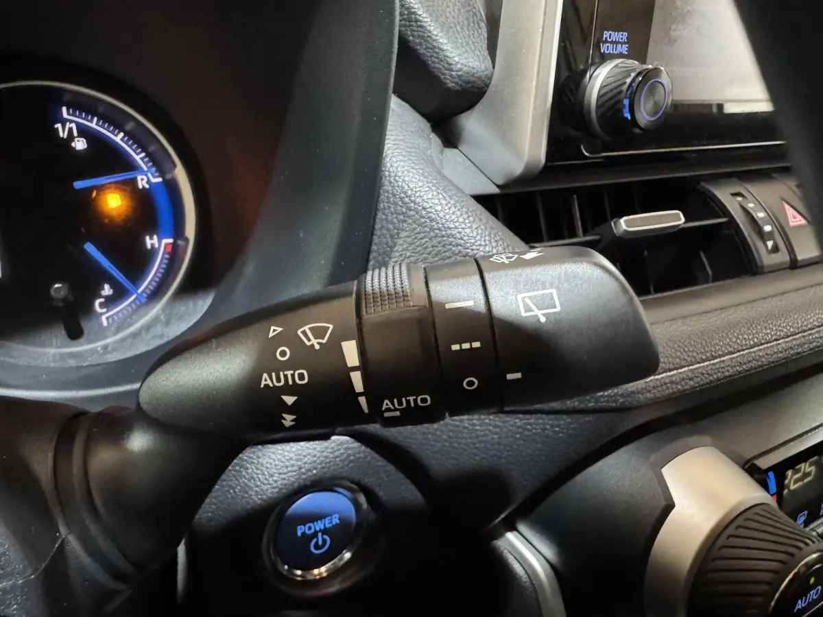 Gros plan sur la commande d'essuie-glace et le bouton Power bleu du tableau de bord intérieur du Toyota RAV4 gris clair hybride 2021.