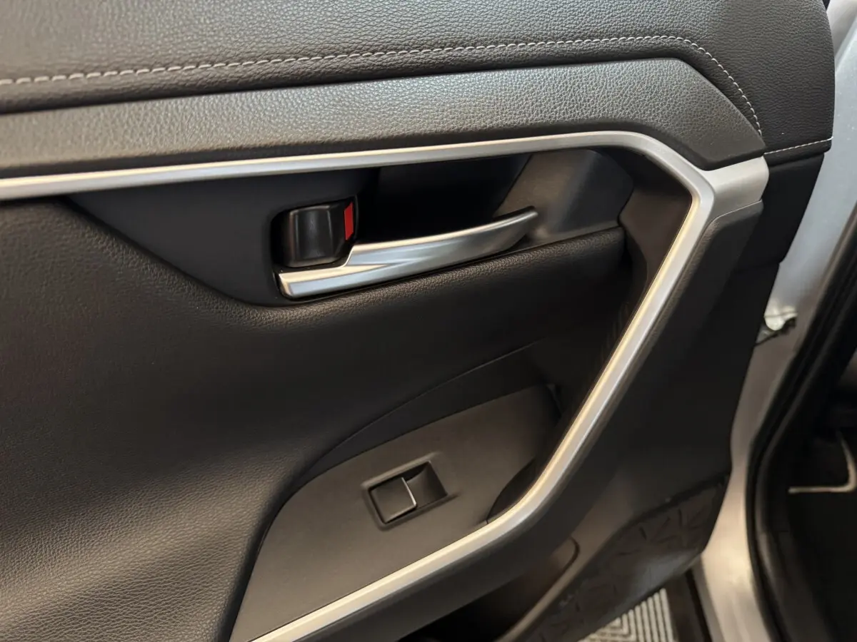 Poignée intérieure côté gauche en métal brossé sur porte noire du Toyota RAV4 Hybride 2021.