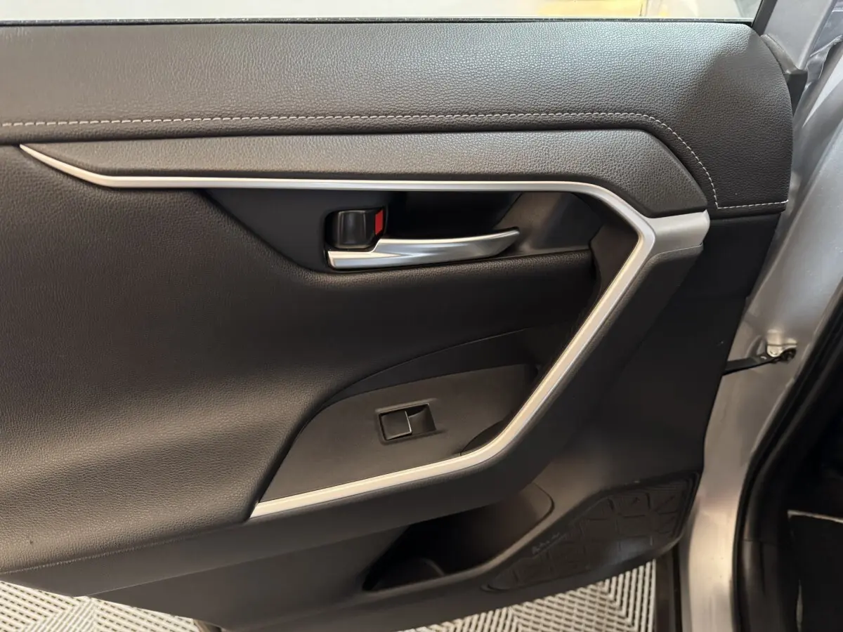 Gros plan sur la porte intérieure côté droit du Toyota RAV4 gris clair, avec poignée argentée et garniture noire.