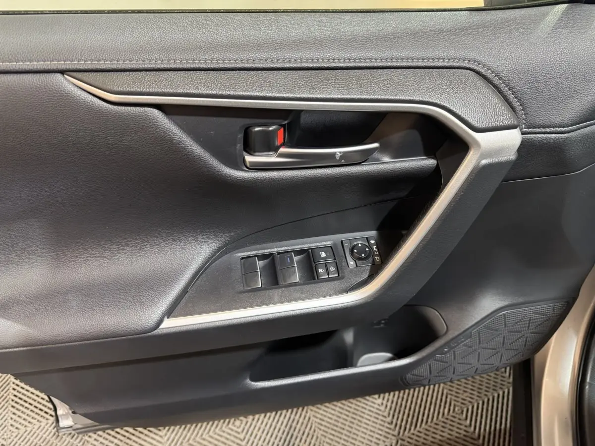 Gros plan sur la porte avant gauche noire du Toyota RAV4 hybride 2021 avec commandes électriques et poignée argentée.