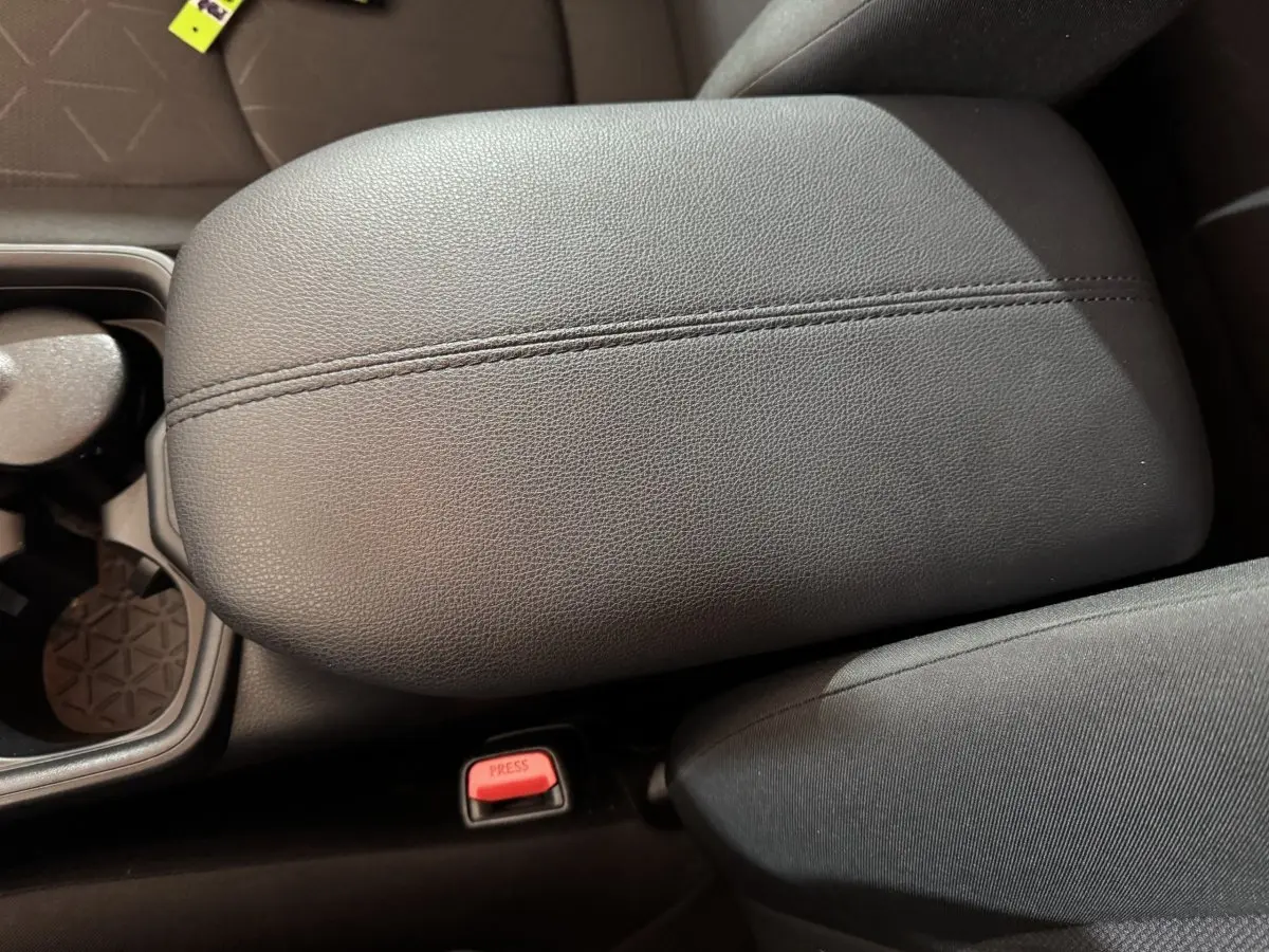 Accoudoir central en cuir noir avec bouton de ceinture rouge, intérieur du Toyota RAV4 hybride 2021.