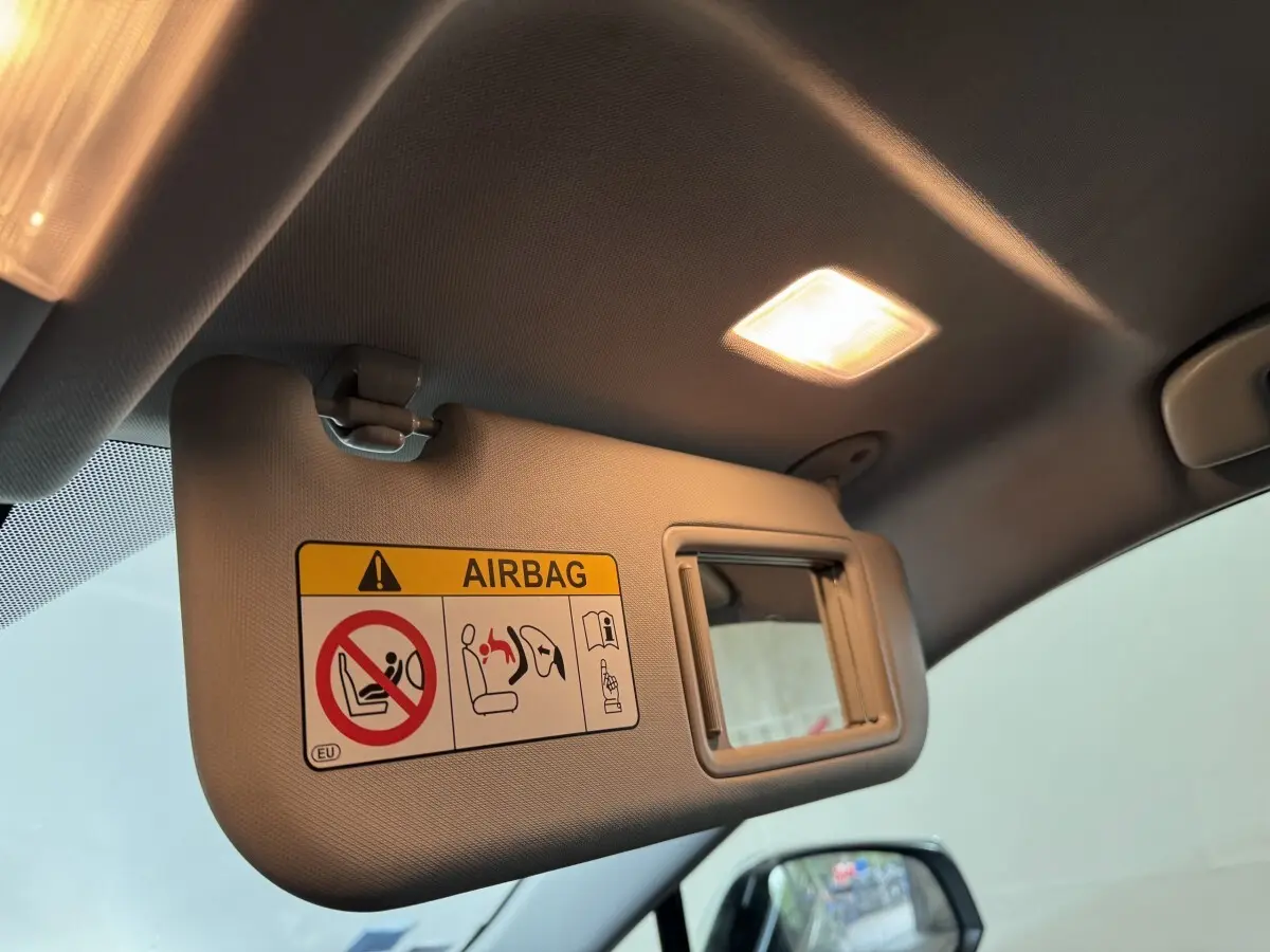 Détail du pare-soleil côté conducteur avec miroir et avertissement airbag dans un Toyota RAV4 gris clair 2021 hybride.