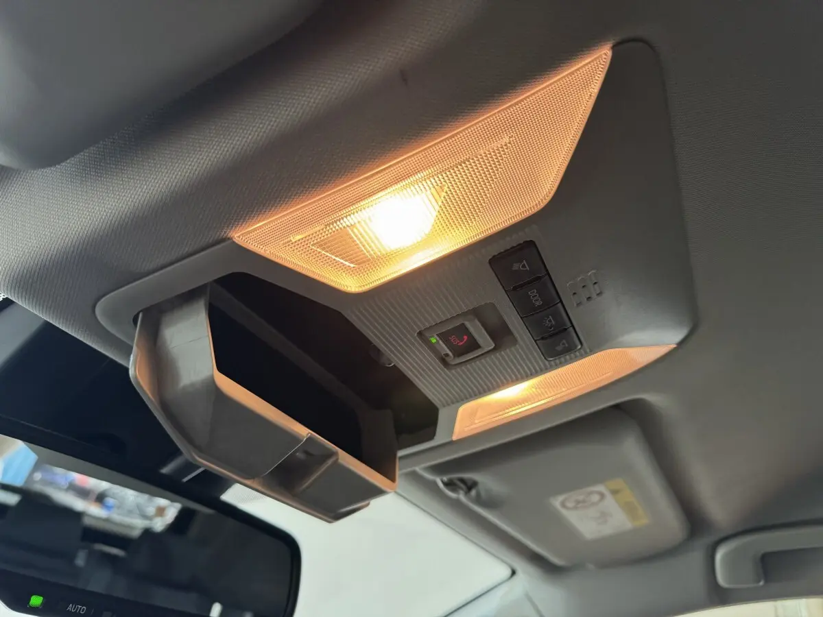 Vue intérieure du plafonnier allumé avec rangement lunettes ouvert dans un Toyota RAV4 hybride gris clair 2021.