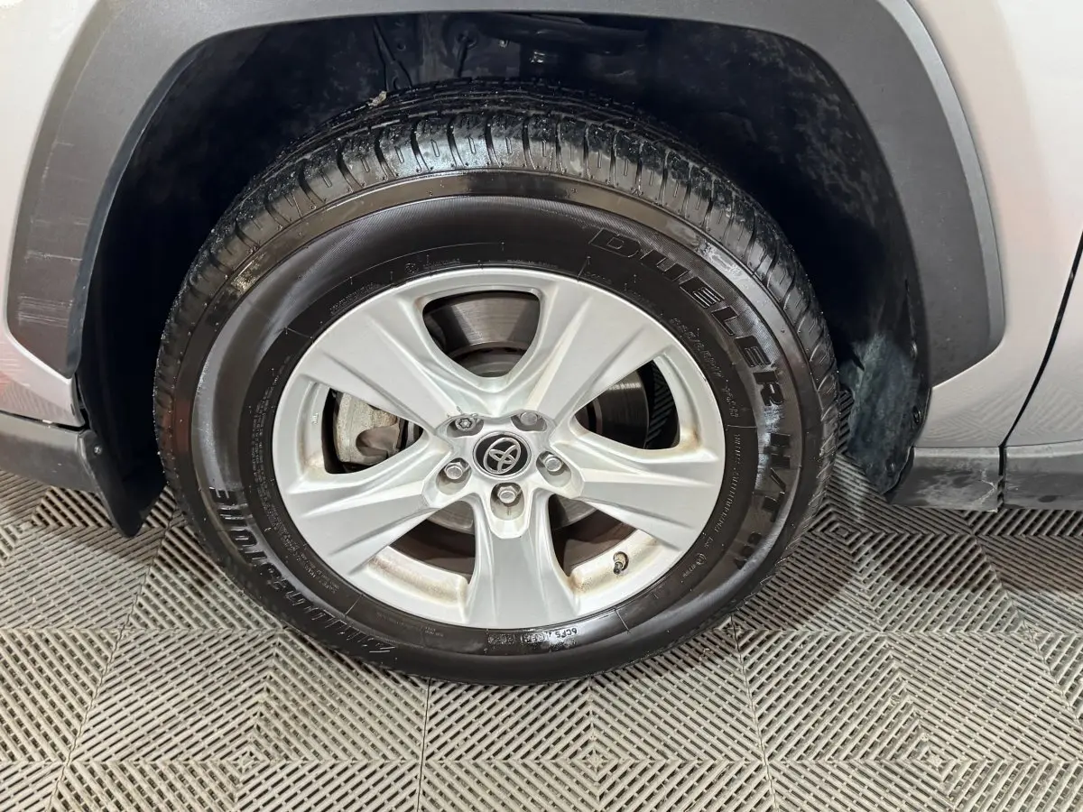 Gros plan sur la roue avant gauche du Toyota RAV4 gris clair, mettant en valeur la jante alliage et le pneu Bridgestone.